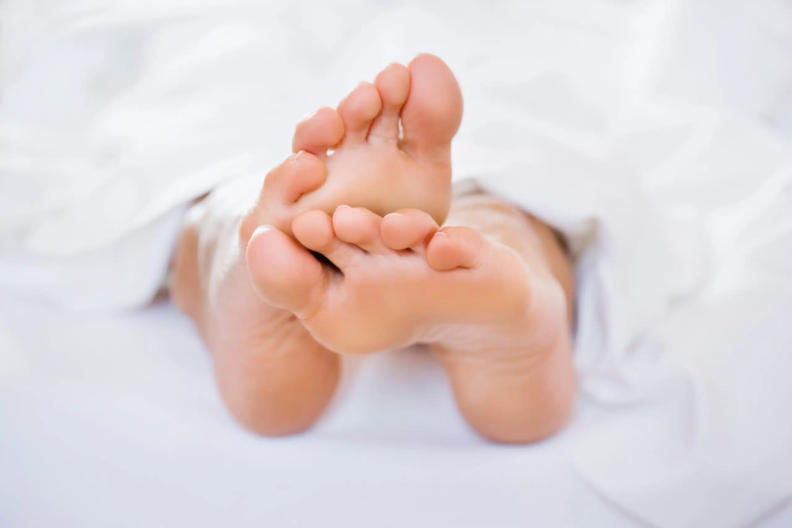Naked feet in white sheets